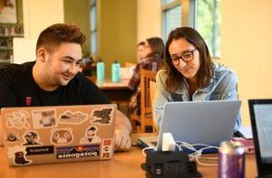 Two students work on laptops.